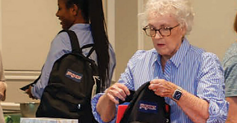 Moorings Park resident filling a backpack with school supplies
