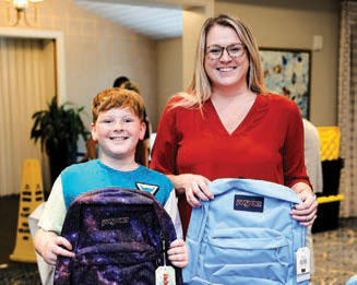 Mother and son holding the backpacks they received at the backpack event