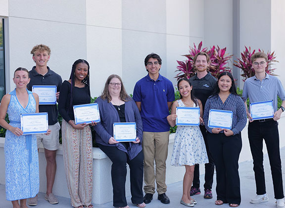 A group of Moorings Park employees standing together all are holding certificates